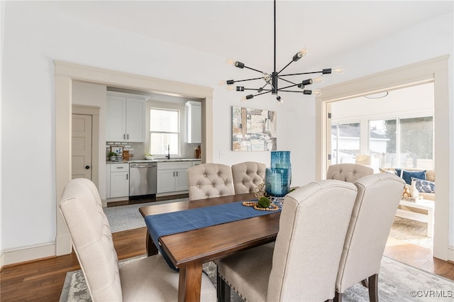 dining area featuring light wood-type flooring, sink, a wealth of natural light, and a chandelier