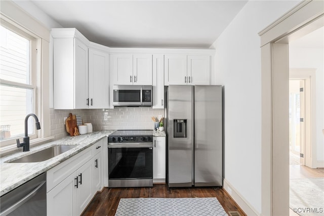 kitchen featuring white cabinets, stainless steel appliances, light stone countertops, and sink