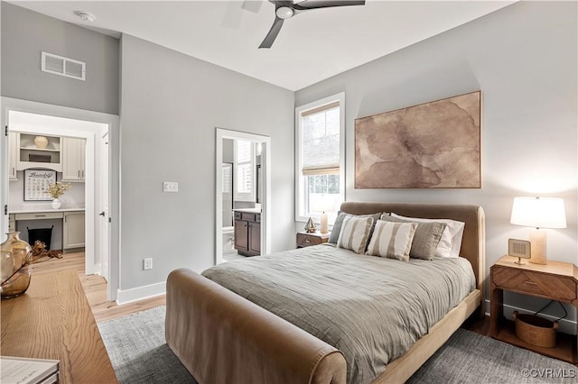 bedroom with connected bathroom, ceiling fan, and light hardwood / wood-style flooring