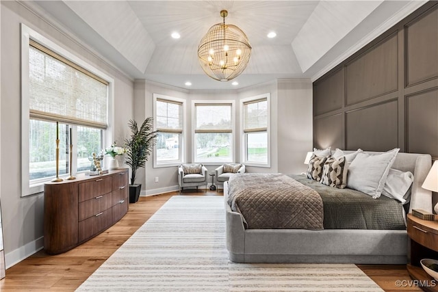 bedroom featuring a tray ceiling, ornamental molding, a chandelier, and light wood-type flooring