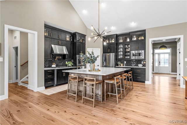 kitchen with a kitchen breakfast bar, light hardwood / wood-style flooring, a kitchen island, and appliances with stainless steel finishes