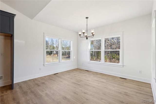 unfurnished dining area with vaulted ceiling, a chandelier, and hardwood / wood-style floors