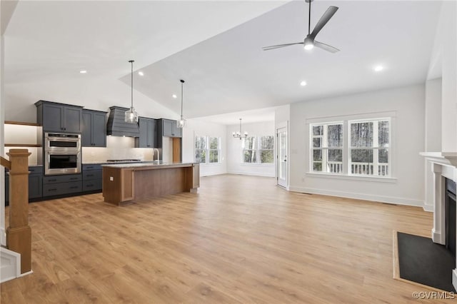 kitchen featuring premium range hood, hardwood / wood-style floors, stainless steel appliances, ceiling fan with notable chandelier, and a center island