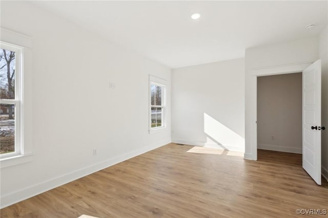 empty room with light hardwood / wood-style floors and a healthy amount of sunlight