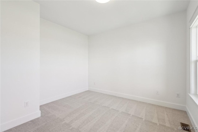 unfurnished room with light colored carpet and plenty of natural light