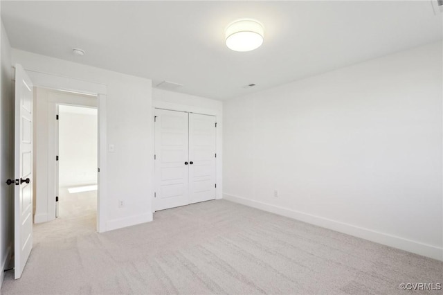 unfurnished bedroom featuring light colored carpet and a closet