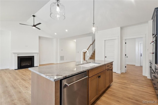 kitchen with a center island with sink, dishwasher, hanging light fixtures, light stone countertops, and sink