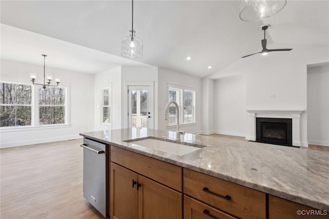 kitchen with dishwasher, sink, light stone counters, and pendant lighting