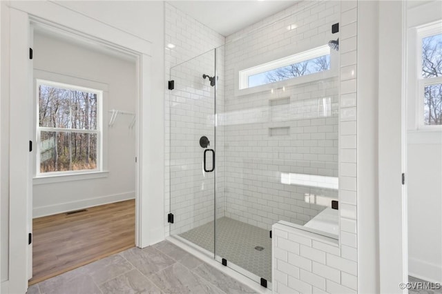 bathroom with tile patterned flooring, a healthy amount of sunlight, and a shower with shower door