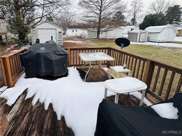 snow covered deck with area for grilling, a yard, and an outbuilding