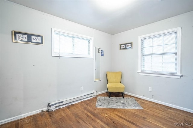 living area with wood-type flooring and baseboard heating