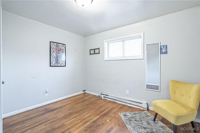 living area with hardwood / wood-style floors and a baseboard heating unit