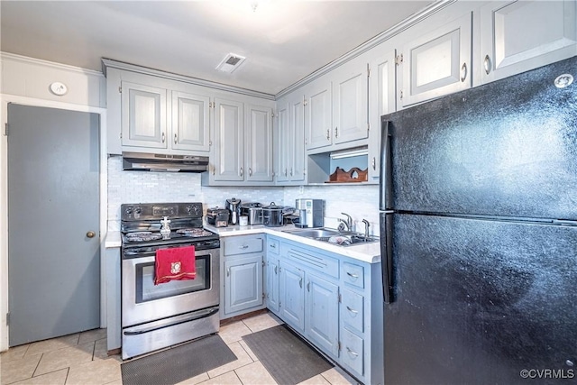 kitchen with sink, black fridge, stainless steel range with electric stovetop, decorative backsplash, and light tile patterned floors