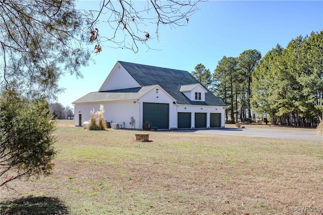 rear view of property featuring a garage and a lawn