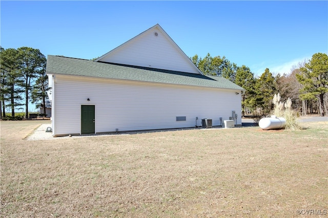 back of house featuring central AC unit and a lawn