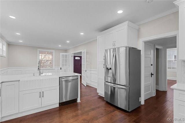 kitchen with stainless steel appliances, white cabinetry, a wealth of natural light, and crown molding