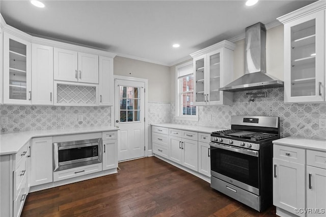 kitchen with stainless steel appliances, wall chimney range hood, and white cabinetry