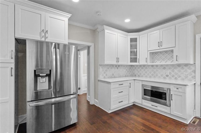 kitchen featuring stainless steel appliances, ornamental molding, dark hardwood / wood-style flooring, decorative backsplash, and white cabinetry