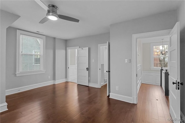 unfurnished bedroom featuring dark wood-type flooring and ceiling fan with notable chandelier