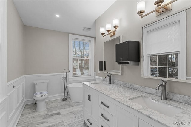 bathroom with toilet, vanity, and a bathtub