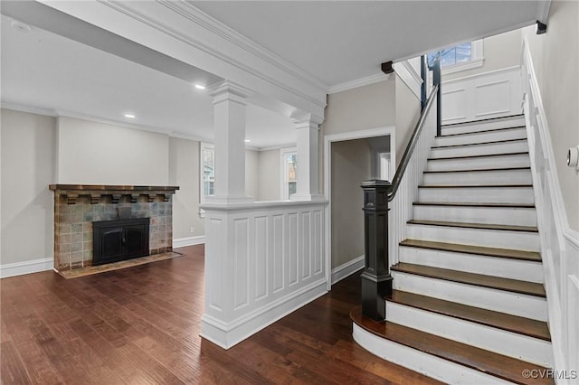 staircase with a tile fireplace, crown molding, and hardwood / wood-style flooring