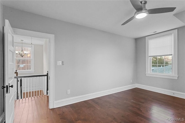 unfurnished room with ceiling fan with notable chandelier and dark hardwood / wood-style floors