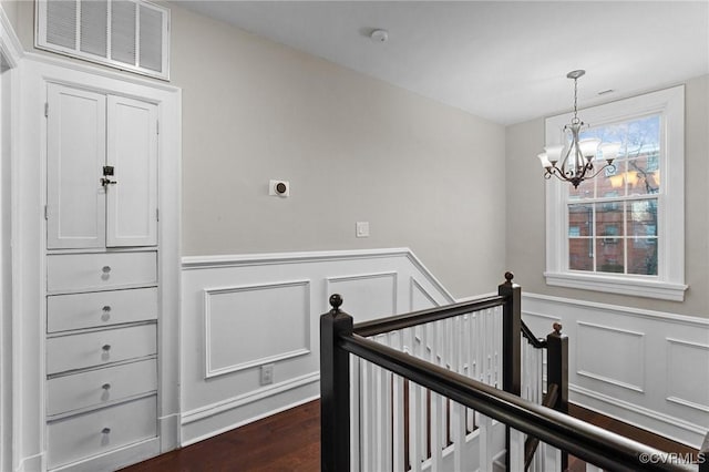 staircase with wood-type flooring and a notable chandelier