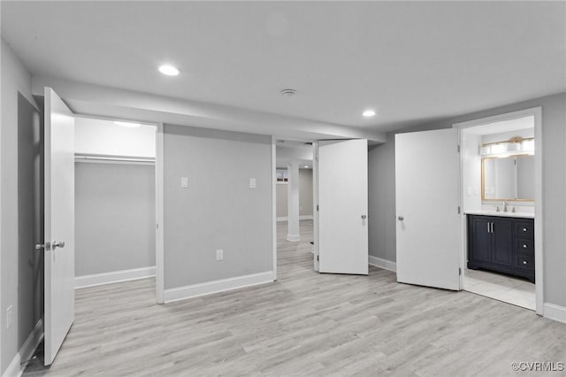 unfurnished bedroom with ensuite bathroom, a closet, light hardwood / wood-style flooring, and sink