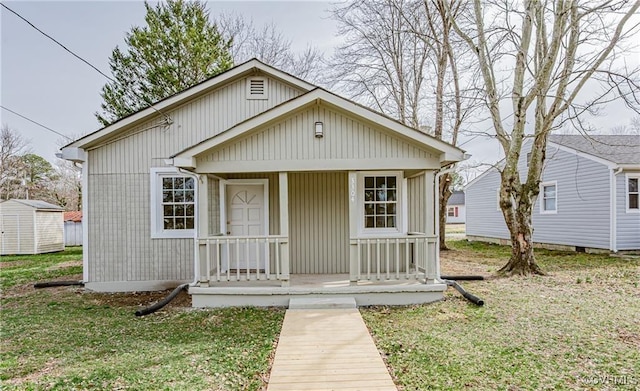 bungalow-style house with a porch, a storage unit, and a front lawn