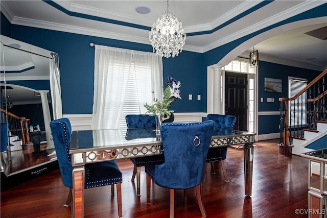 dining area with dark wood-type flooring, a raised ceiling, and crown molding