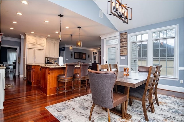 dining space featuring dark hardwood / wood-style flooring, an inviting chandelier, ornamental molding, and vaulted ceiling