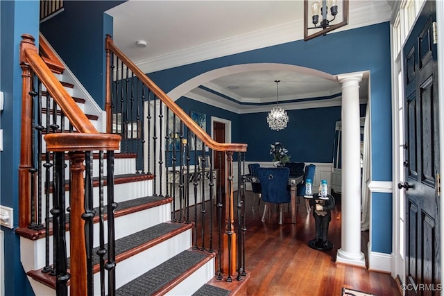 staircase with crown molding, a chandelier, and wood-type flooring