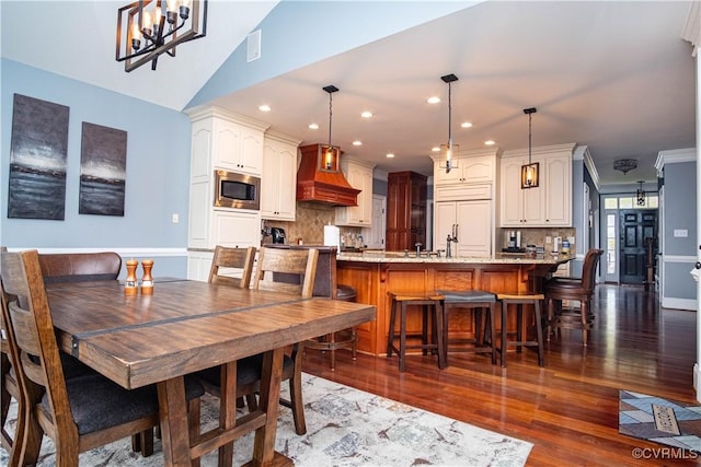 dining area featuring ornamental molding, dark wood-type flooring, and vaulted ceiling