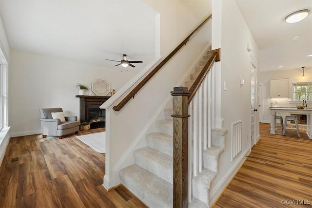 stairs with ceiling fan and hardwood / wood-style floors