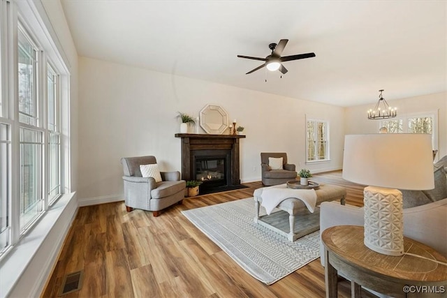 living room with ceiling fan with notable chandelier and wood-type flooring