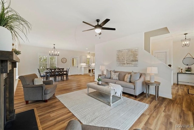 living room with hardwood / wood-style floors and ceiling fan with notable chandelier