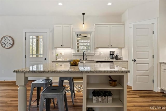 kitchen featuring light stone countertops, a kitchen island, and hanging light fixtures