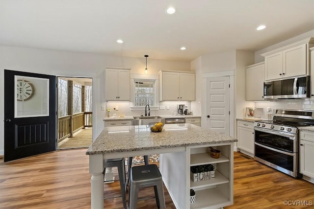 kitchen with white cabinetry, a center island, sink, stainless steel appliances, and pendant lighting