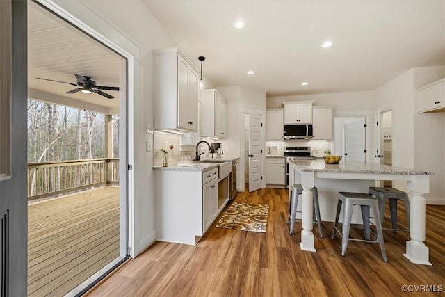 kitchen with ceiling fan, hanging light fixtures, light hardwood / wood-style floors, white cabinets, and appliances with stainless steel finishes