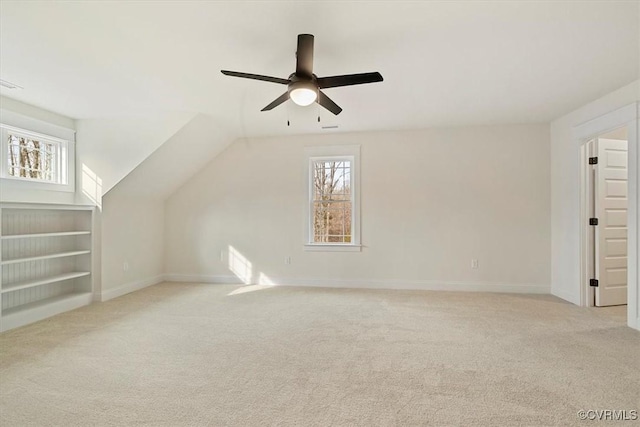 additional living space with light carpet, vaulted ceiling, plenty of natural light, and ceiling fan