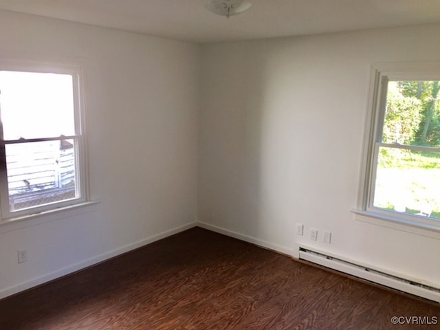 spare room with dark wood-type flooring and a baseboard radiator