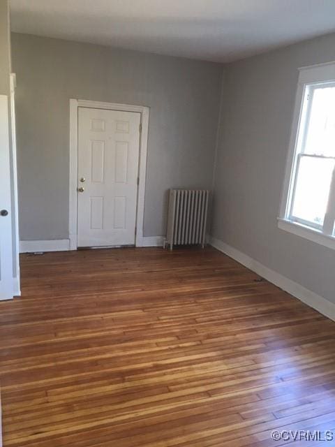 spare room featuring wood-type flooring and radiator