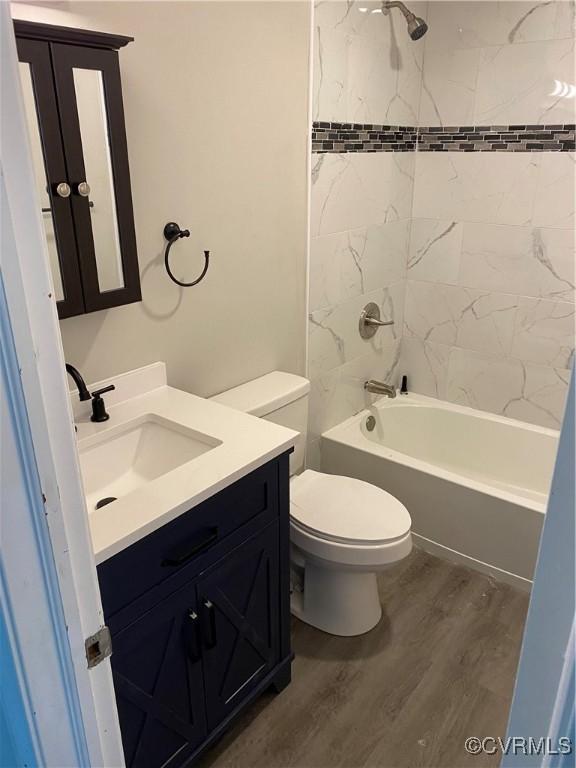 full bathroom featuring toilet, hardwood / wood-style floors, vanity, and tiled shower / bath combo