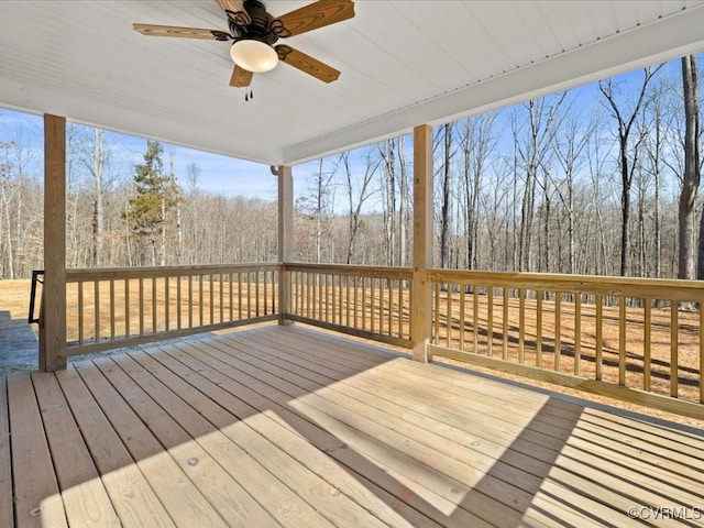 wooden deck featuring a ceiling fan and a wooded view