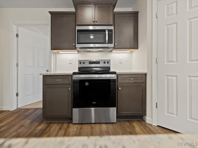 kitchen featuring stainless steel appliances, dark wood-type flooring, dark brown cabinetry, and tasteful backsplash