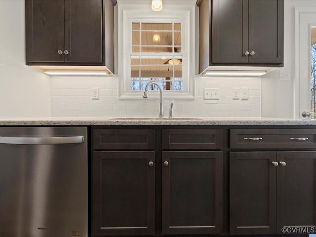 kitchen with light stone counters, dark brown cabinetry, a sink, stainless steel dishwasher, and backsplash