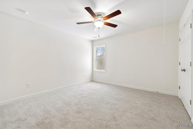 carpeted empty room featuring a ceiling fan, attic access, and baseboards