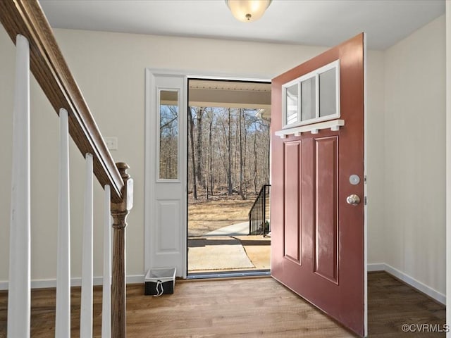 foyer entrance with stairs, baseboards, and wood finished floors