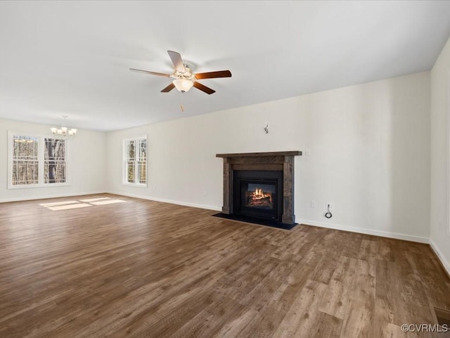 unfurnished living room with a fireplace with flush hearth, ceiling fan with notable chandelier, baseboards, and wood finished floors