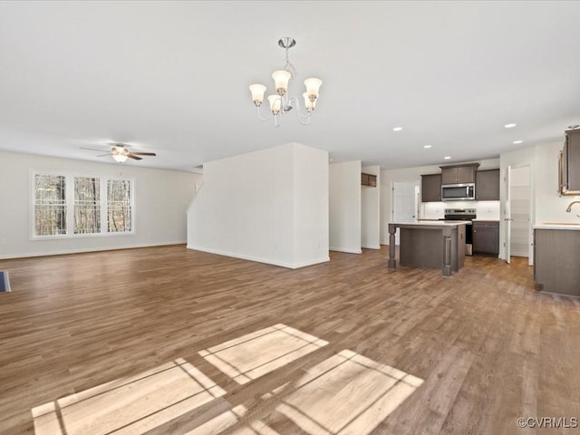 unfurnished living room featuring visible vents, baseboards, wood finished floors, ceiling fan with notable chandelier, and recessed lighting